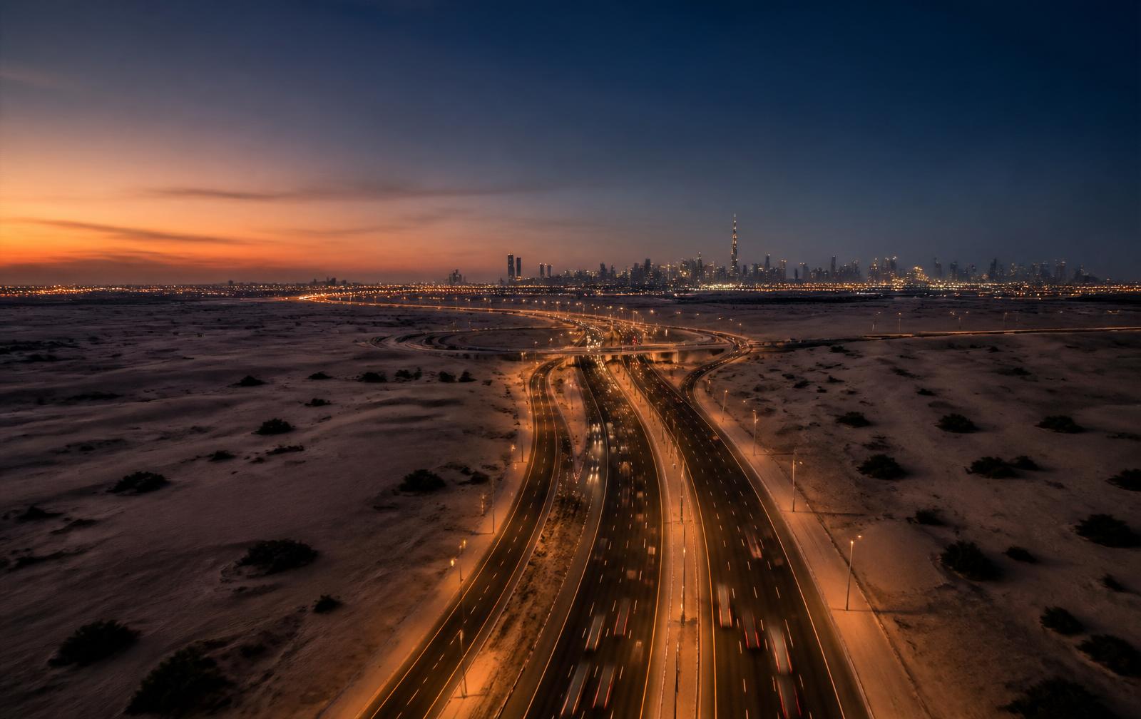Aerial view of a UAE highway at dusk with the Dubai skyline on the horizon